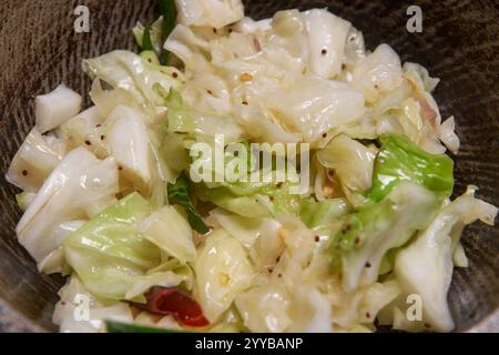 close-up of cooking or tempered cabbage dish, chopped cabbage mixed with mustard seeds, onions and red chili, preparing flavorful healthy food Stock Photo