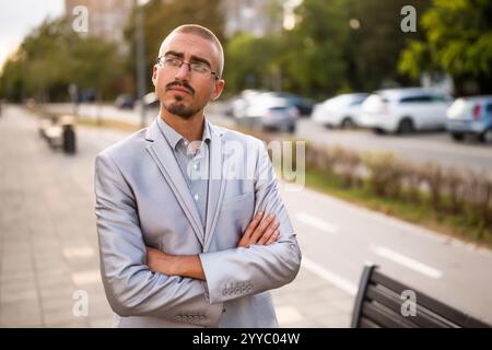 Portrait of thoughtful and distraught young businessman who is standing in the street and looking away. Stock Photo