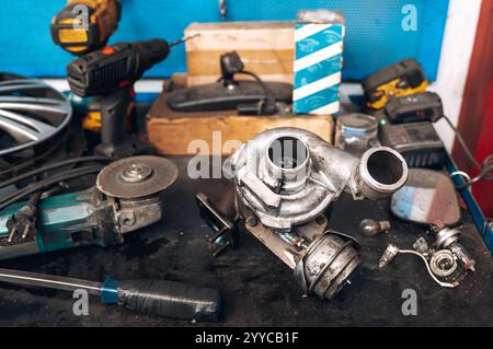 Turbocharger placed on workbench amidst tools and parts, showcasing automotive repair process Stock Photo