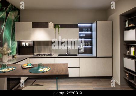 Modern and stylish kitchen with white and brown cabinets, island, and tropical wallpaper, showcasing contemporary interior design Stock Photo