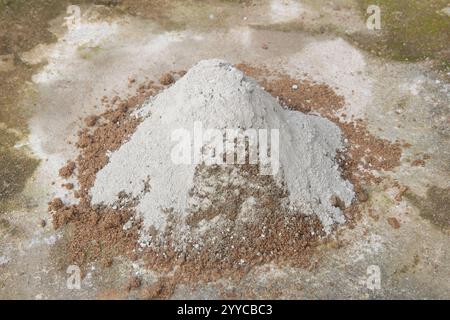 pile of sand with dry powdered cement poured on top outdoors, step preparing concrete in selective focus with copy space Stock Photo