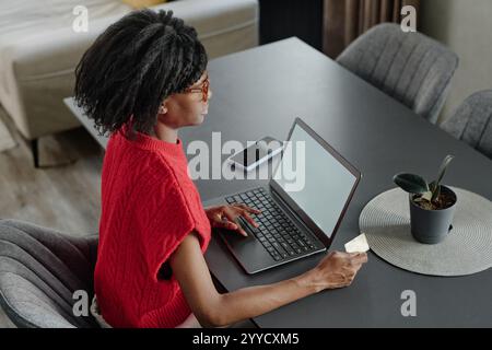 High angle shot of elegant African American woman sitting on chair and focused on online shopping at home Stock Photo