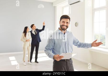 Confident realtor agent and clients, architect, interior designer showing new empty apartment plan  Stock Photo