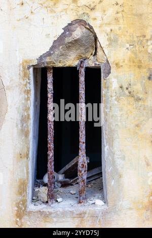 Rusty Bars on an Old Yellow Building with Weathered and Cracked Plaster Stock Photo