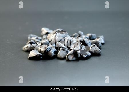 Tumbled close up snowflake obsidian on grey textured background top view Stock Photo