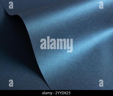 Shimmering dark blue paper texture with a metallic gloss and wavy shapes. The smooth, reflective surface features a satin gradient and subtle sparkle, Stock Photo