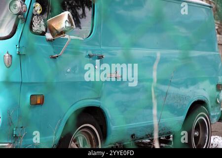 Old Chevy 90 van, behind chain link fence Stock Photo