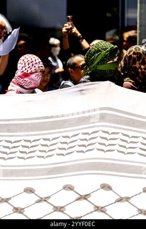 Protesters, some wearing face coverings, march through a street as a ...