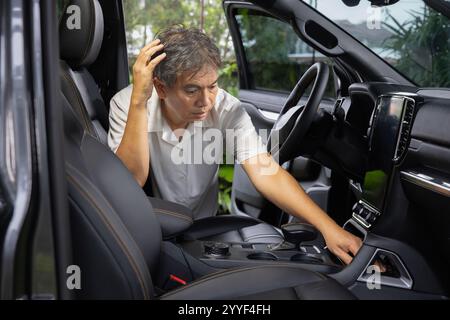 Senior asian man look for a key inside car. Stock Photo