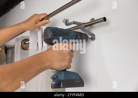 Worker repairman hanging and fixing the curtain on the window Stock Photo