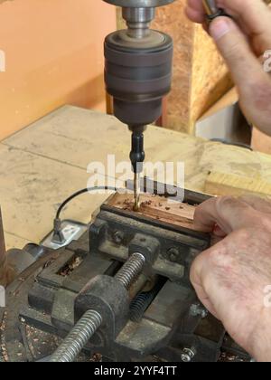 Wood worker man using drill press machine for make a hole on wood parts in vise. Stock Photo