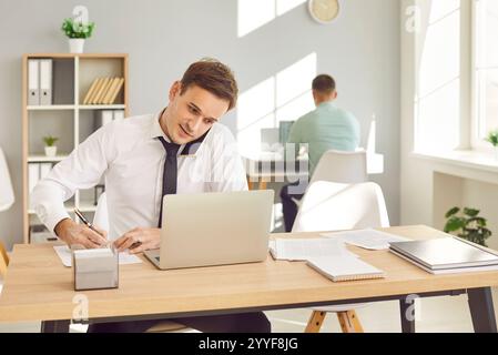 Man Businessman Working In Office With Laptop, Talking On Phone With Client Stock Photo