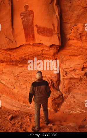 Hiker at ‘Crowned Figure’ pictograph, Barrier Canyon Style, at Hog Springs, Bicentennial Highway aka Trail of The Ancients Byway, Trachyte Point area, Utah, USA Stock Photo