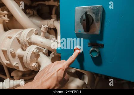 Hand activating emergency stop button on heavy machinery control panel in factory Stock Photo