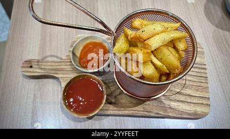 Aerial view of seasoned french fries on traditional plate with chili and tomato sauce near. Seasoned french fries quite popular snack for teenager Stock Photo