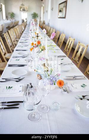 Banquet table in rustic European style. White tablecloth and empty glasses and plates. Stock Photo