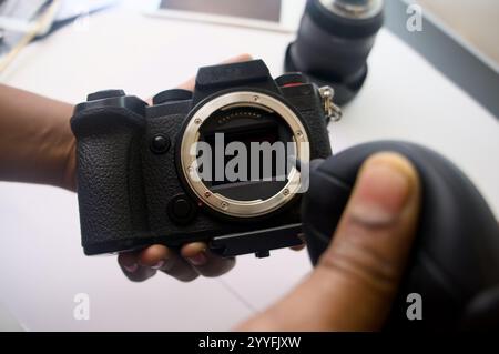 Hands cleaning a mirrorless camera sensor with a blower. Maintaining equipment for optimal performance. Stock Photo