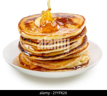 Pancakes and honey pouring over them on white plate. File contains clipping path Stock Photo