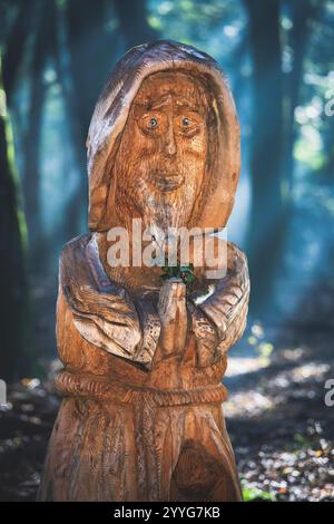 Carving a human face, portrait or statue in a tree trunk, sculpting is one of the handcrafts made by a lumberjack with a chainsaw. Stock Photo