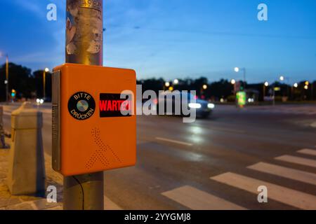 Pedestrian zebra crossing with text telling people to wait and press button in German language Stock Photo