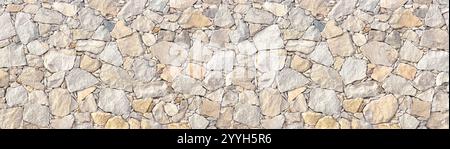 Light brown stone wall in panoramic close-up made of old, roughly hewn, different natural stones Stock Photo