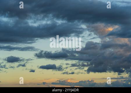 Crescent moon peeking through clouds at sunset. Stock Photo