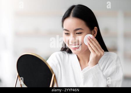 Beautiful asian woman cleaning her face with toner Stock Photo