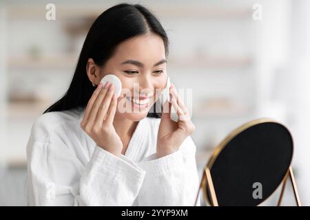 Pretty asian woman cleaning her face with toner Stock Photo