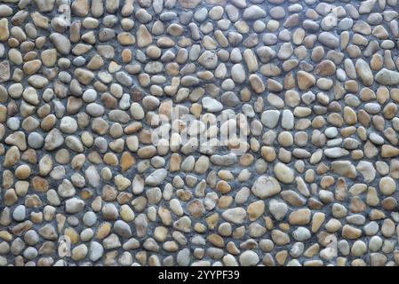 Polished pebble texture for wall decoration. Wall finishing made of gravel and pebbles. Stock Photo