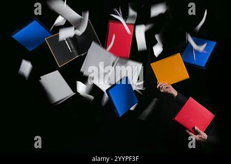 Hands of a man juggling with colorful ring binders and documents, some are flying around, concept for mastering everyday office and business challenge Stock Photo