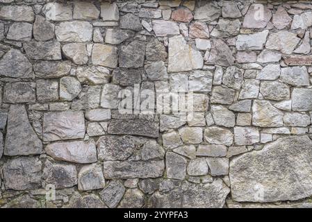 Granite wall made of natural stone. Perfect tiles on all sides. Background of stone wall texture. Stone wall texture background - gray stone siding wi Stock Photo