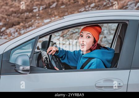 Surprised and happy young woman is holding the steering wheel and driving a car Stock Photo