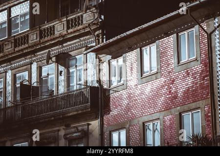 A close-up of traditional Portuguese residential buildings featuring intricate iron balconies, detailed tile facades, and red brick walls reflecting s Stock Photo