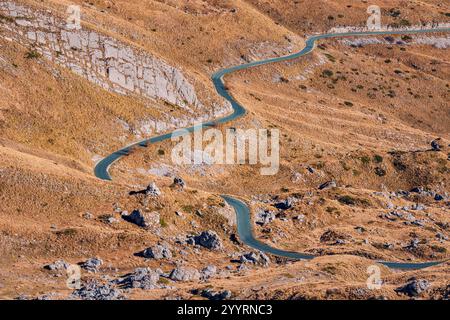 Winding asphalt road passing through dry mountain landscape during sunny autumn day Stock Photo
