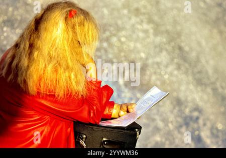 Long blonde hair woman dressed in red reading a document, Munich, Upper Bavaria, Germany Stock Photo