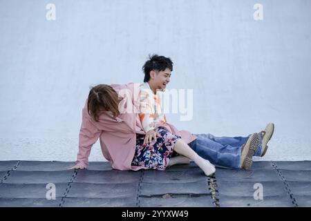 In a large park in Handa City, Aichi Prefecture, a couple in their 20s are having fun playing on a slide that resembles a large hill. Stock Photo