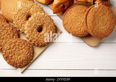 Delicious assortment of freshly baked cookies and pastries on a wooden platter placed on a white wooden table Stock Photo