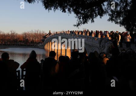 Beijing,China.21th December 2024. The golden red sunset light shines through the 17 arches of the bridge at the Summer Palace in Beijing, December 21, 2024. That day is Winter Solstice, one of the 24 solar terms in China. The 17-arch Bridge is famous for its “golden light piercing the arches” spectacle. Credit: Wang Ziru/China News Service/Alamy Live News Stock Photo