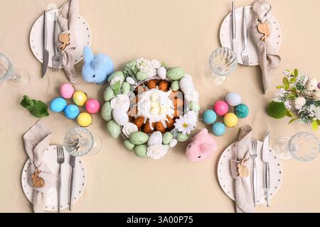Table setting with Easter cake, painted eggs and flowers, top view Stock Photo