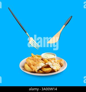 Cutlery in air over plate with British Traditional Fish and potato chips on blue background Stock Photo