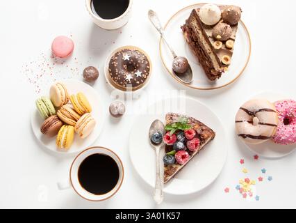 Table with various cookies, donuts, cakes, cheesecakes and coffee cups on white background. Stock Photo