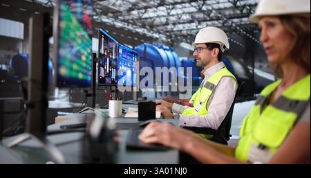 Engineers and operators controlling gas pipes with SCADA software. Professional team maximizing efficiency at power plant with turbine generator. Stock Photo