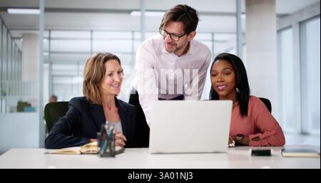 Collaborating Business Team Smiling Together On Laptop In Office Setting Stock Photo