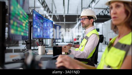 Man and woman control automated machines in diverse factory setting. Stock Photo