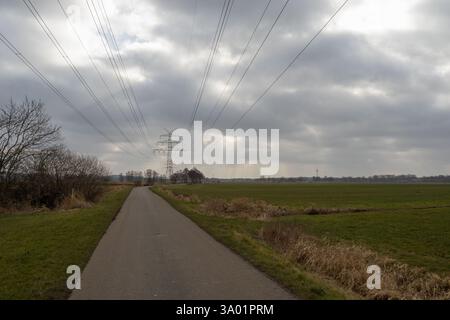 Dramatic sky over power pylons and fields Stock Photo