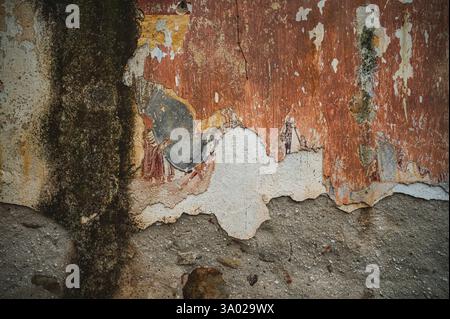 Layers of time revealed: A weathered wall with peeling paint, showing fragments of history and decay, found in a ruined church. Stock Photo