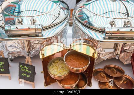 Indian food stall at a market.  Butter chicken (£9) and other dishes served in warming chafing dishes. London Bridge open kitchen street festival Stock Photo