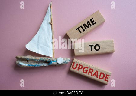 Time to Upgrade symbol. Concept words Time to Upgrade on wooden blocks. Beautiful pink background with boat. Business and Time to Upgrade concept. Cop Stock Photo