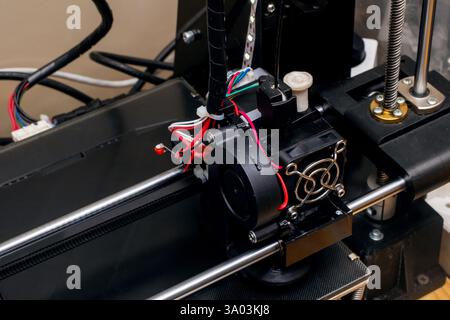 This is a detailed closeup view of a 3D printer equipped with a cooling fan on top of it, showcasing its intricate design and components Stock Photo