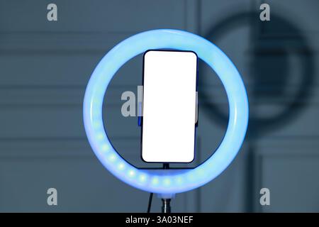 Ring lamp with smartphone against wall indoors Stock Photo